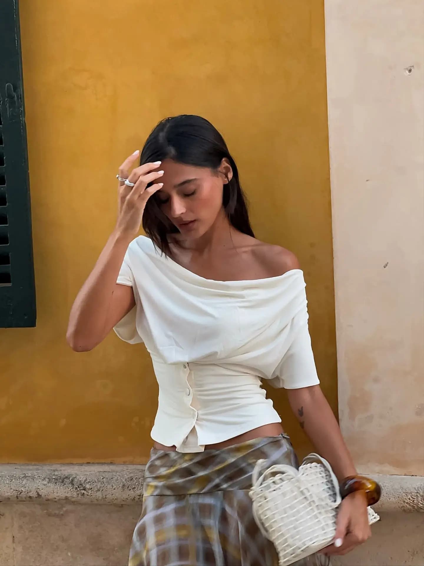 T-shirt beige en jean à taille cintrée, haut noir asymétrique à une épaule et manches courtes